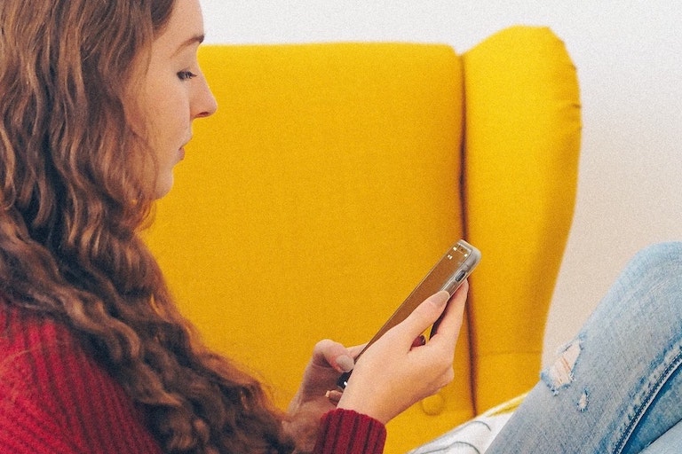 unsplash Foto: Frau sitzt auf Sofa und schaut auf ein Handy