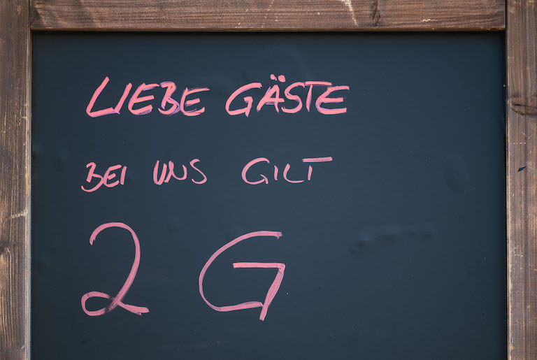 Foto: Vor einem Restaurant hängt ein Schild mit der Aufschrift „Liebe Gäste bei uns gilt 2G“. 