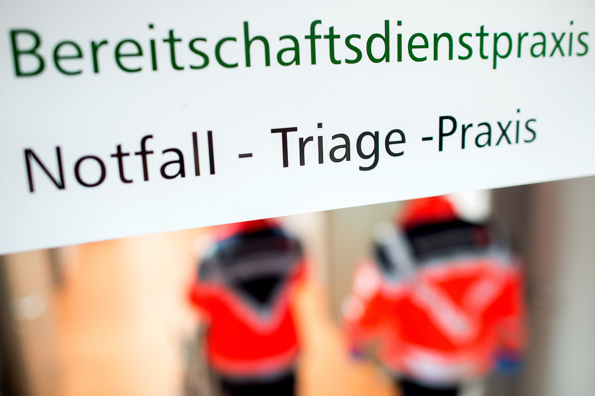 Foto: Die Aufschrift "Notfall-Triage-Praxis" steht auf einem Hinweisschild in einer Klinik.