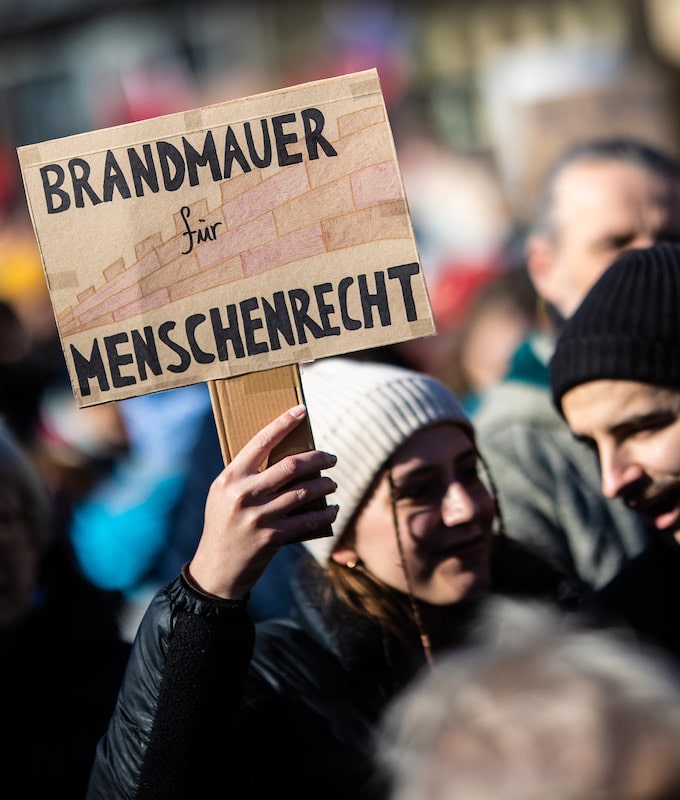 Foto: "Brandmauer für Menschenrecht" steht auf dem Plakat einer Demo-Teilnehmerin in Karlsruhe