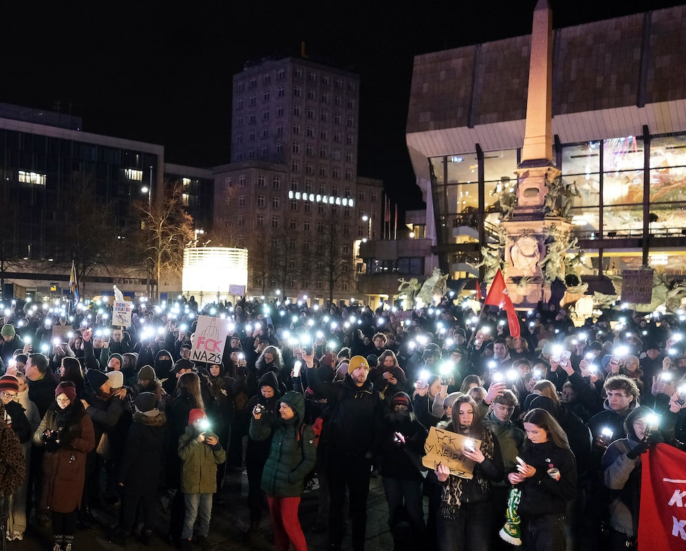 Foto: Zahlreiche Menschen vdemonstrieren auf dem Augustusplatz in Leipzig und leuchten mit ihren Smartphones.