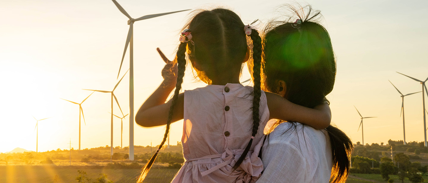 Foto: Mutter und Tochter schauen auf Windpark bei Sonnenuntergang